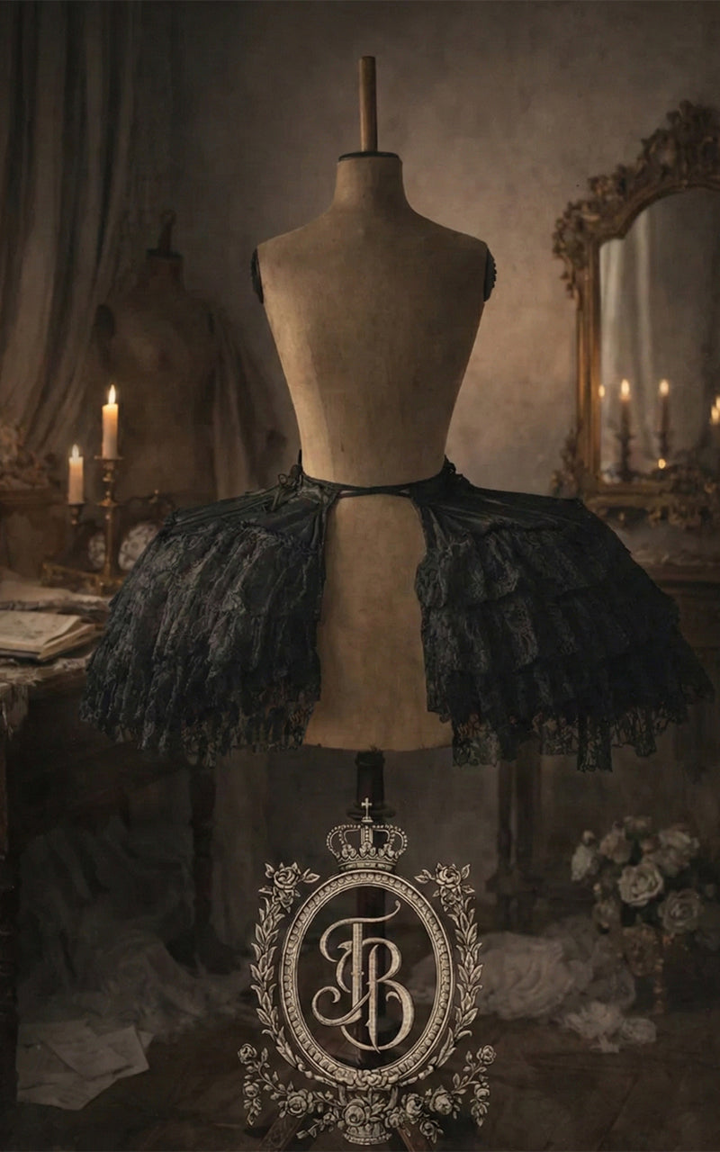 Mannequin wearing a black lace pannier with a decorative logo in a vintage setting.