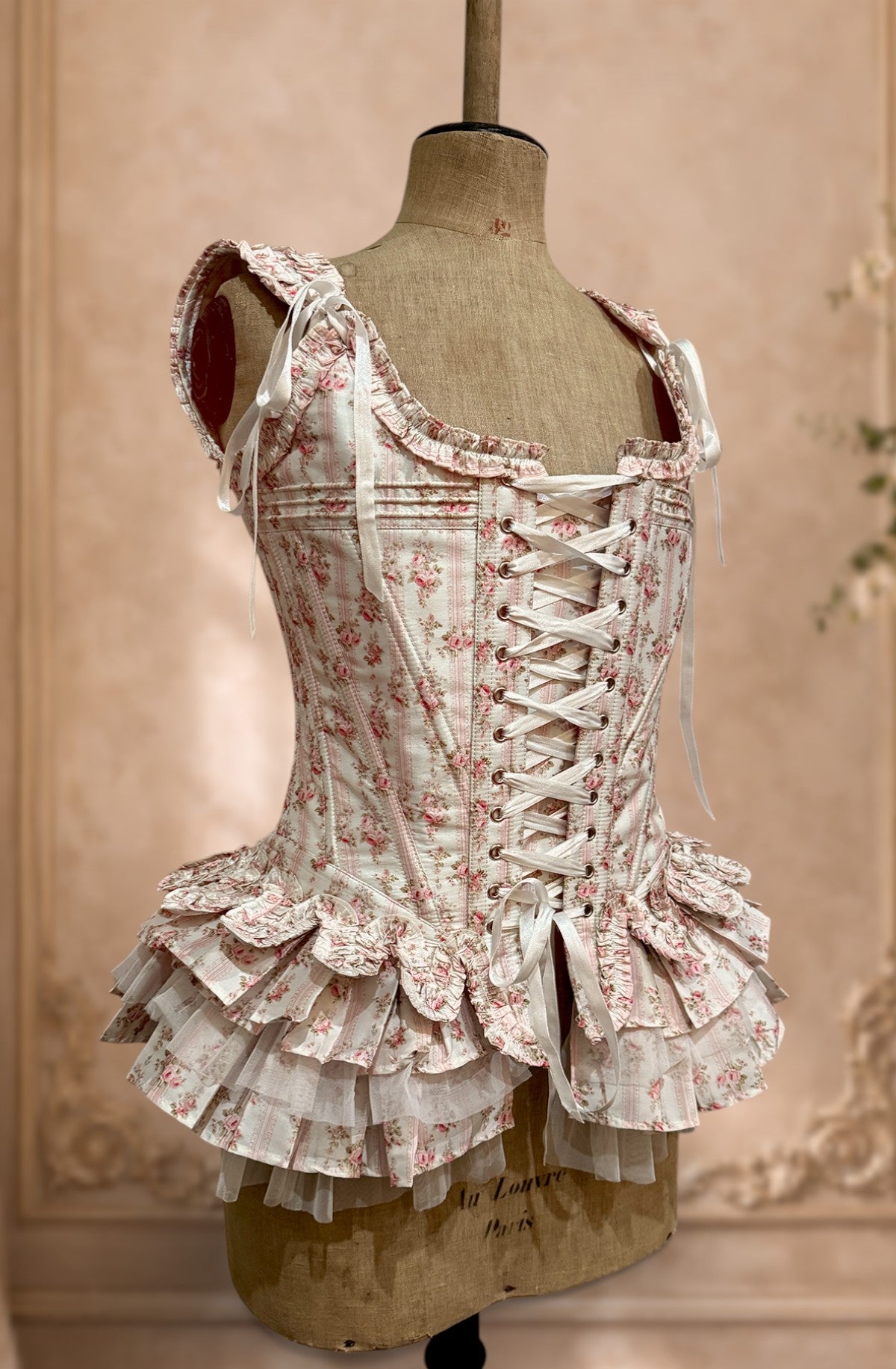 Floral french corset with peplum on a mannequin against a beige wall