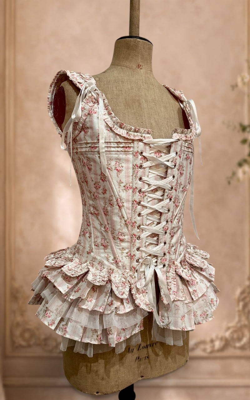 Floral french corset with peplum on a mannequin against a beige wall