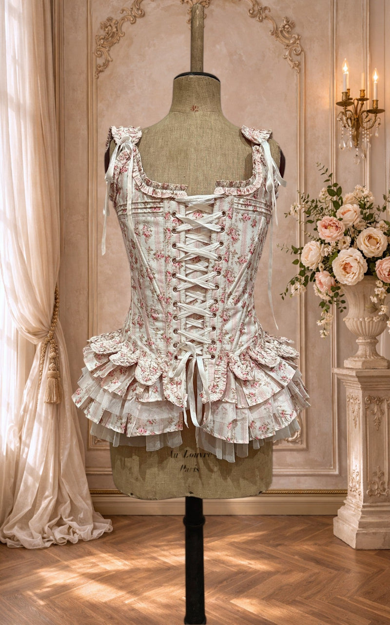 Delicate corset with peplum on a mannequin in an elegant room with floral decorations.